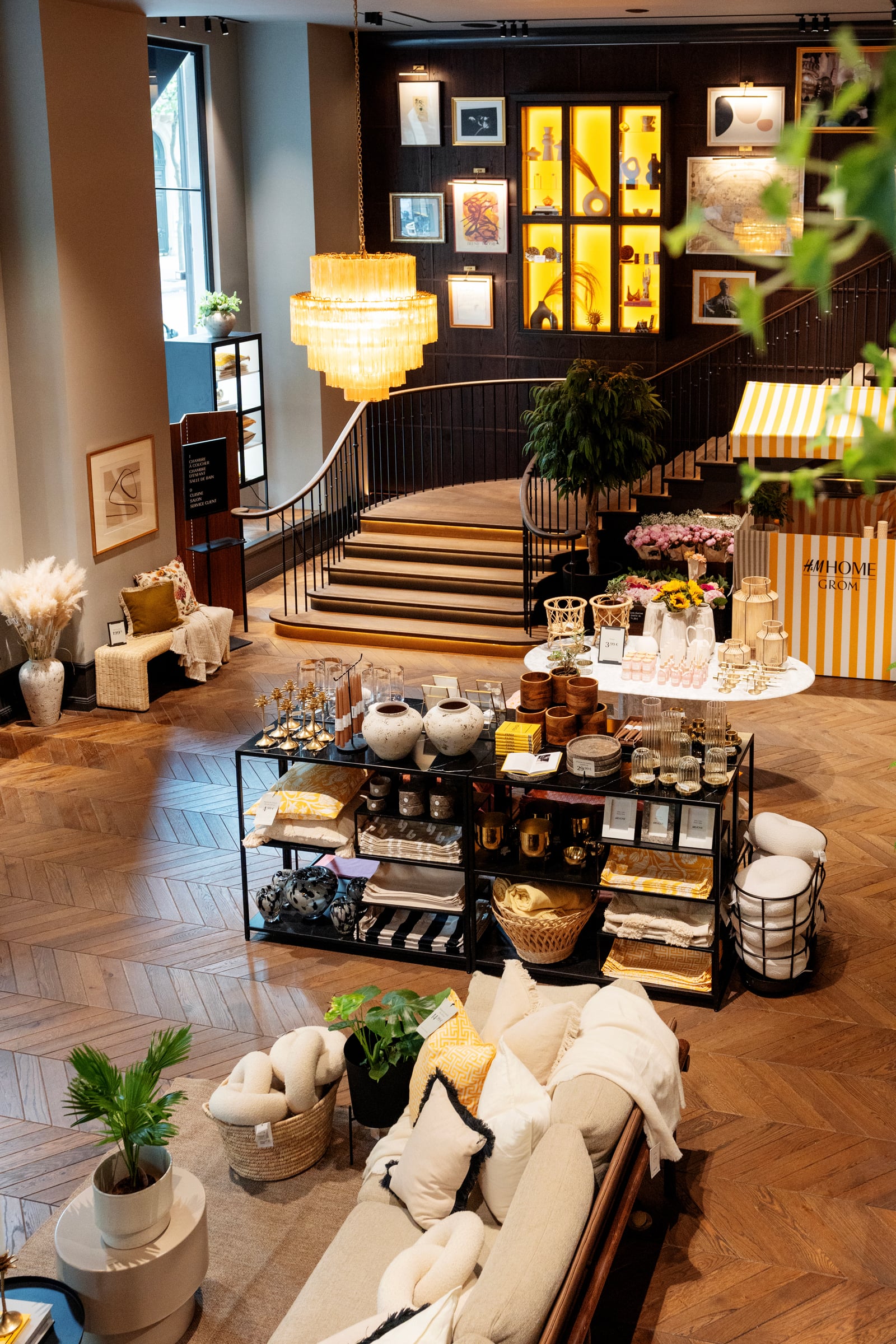 Intérieur de la boutique H&M Home avec escalier, lustres et tables d'exposition