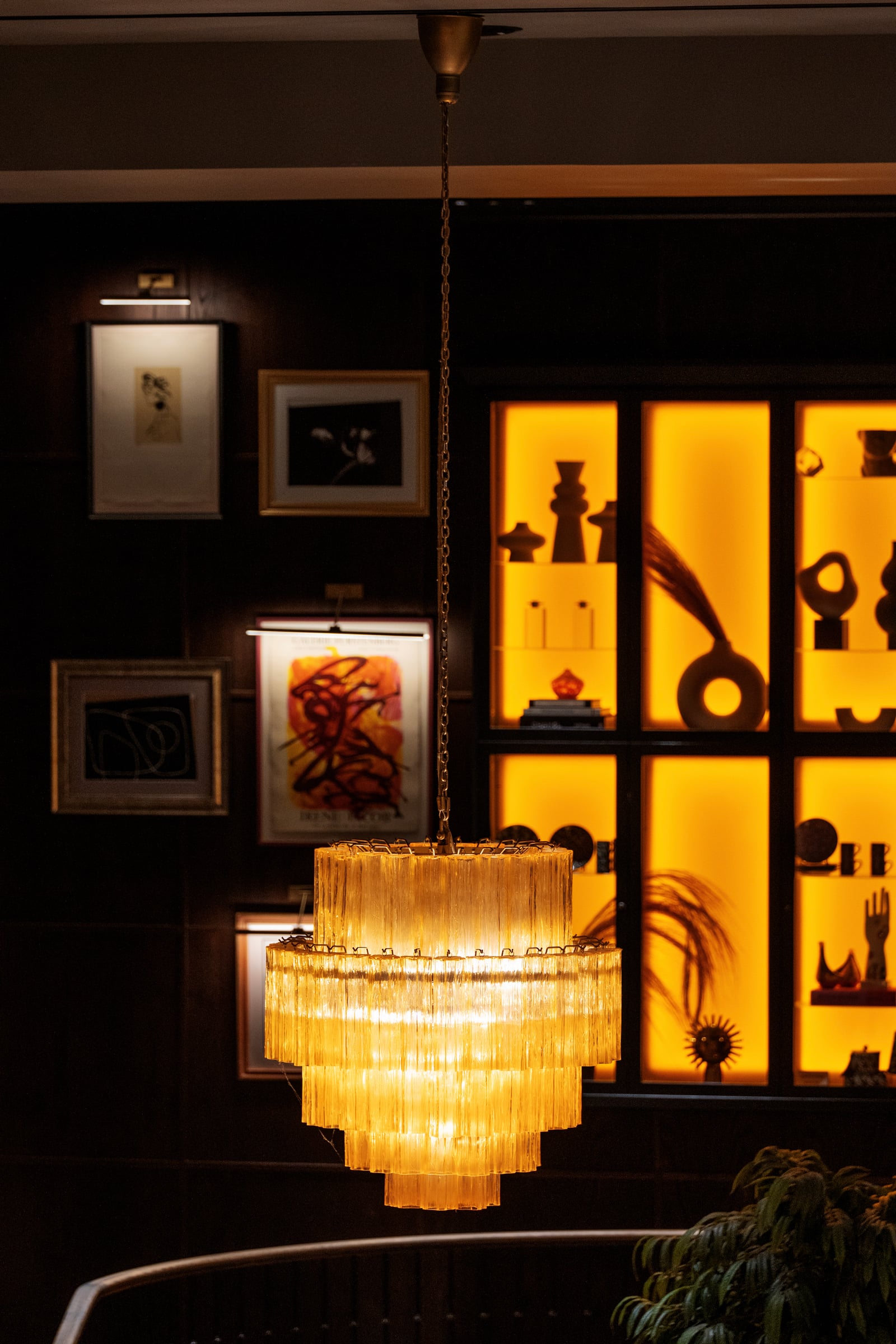 Lustre doré devant des étagères éclairées en jaune, boutique H&M Home