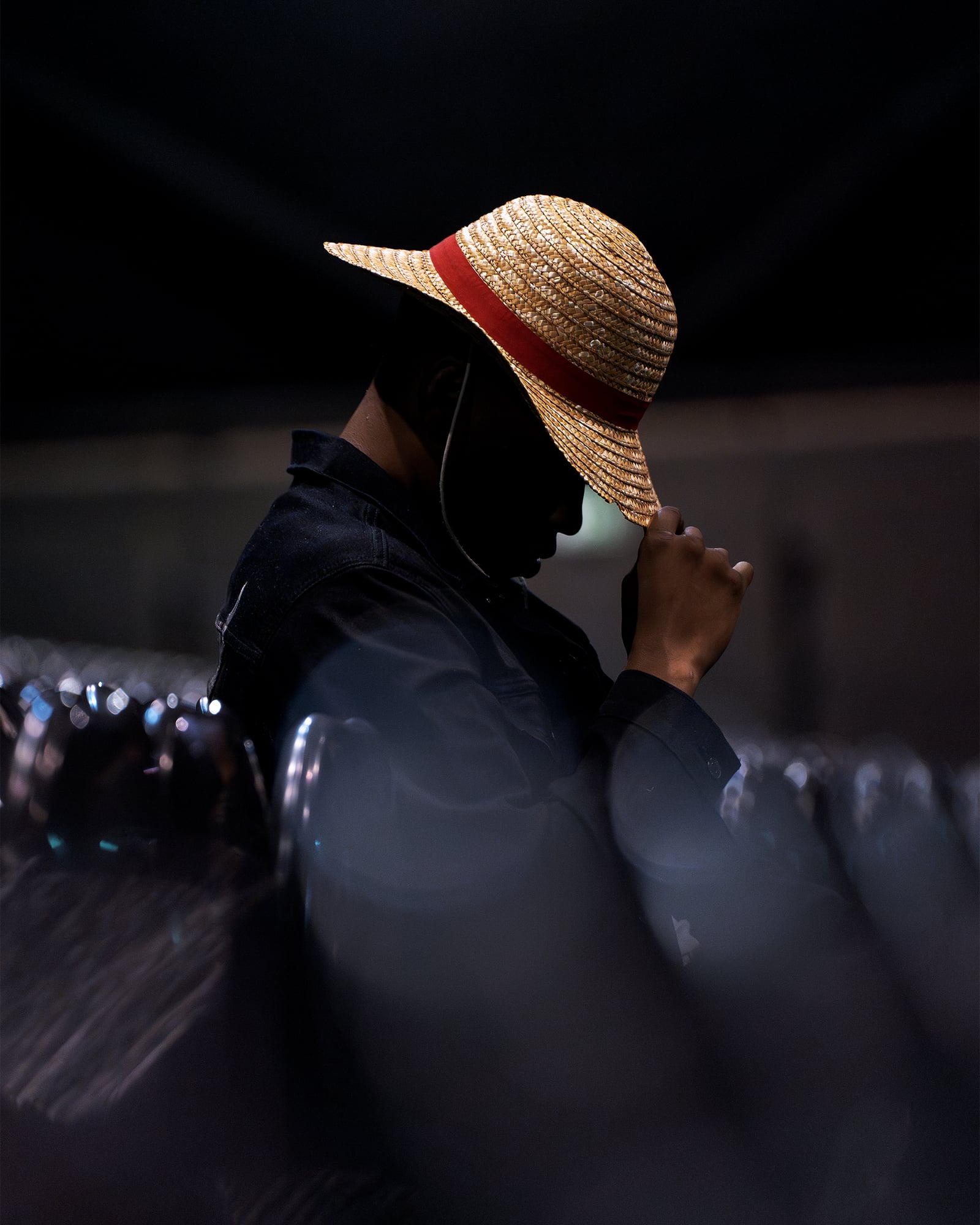 Patrick Habirora ajustant son chapeau de paille dans la pénombre d'une salle de spectacle