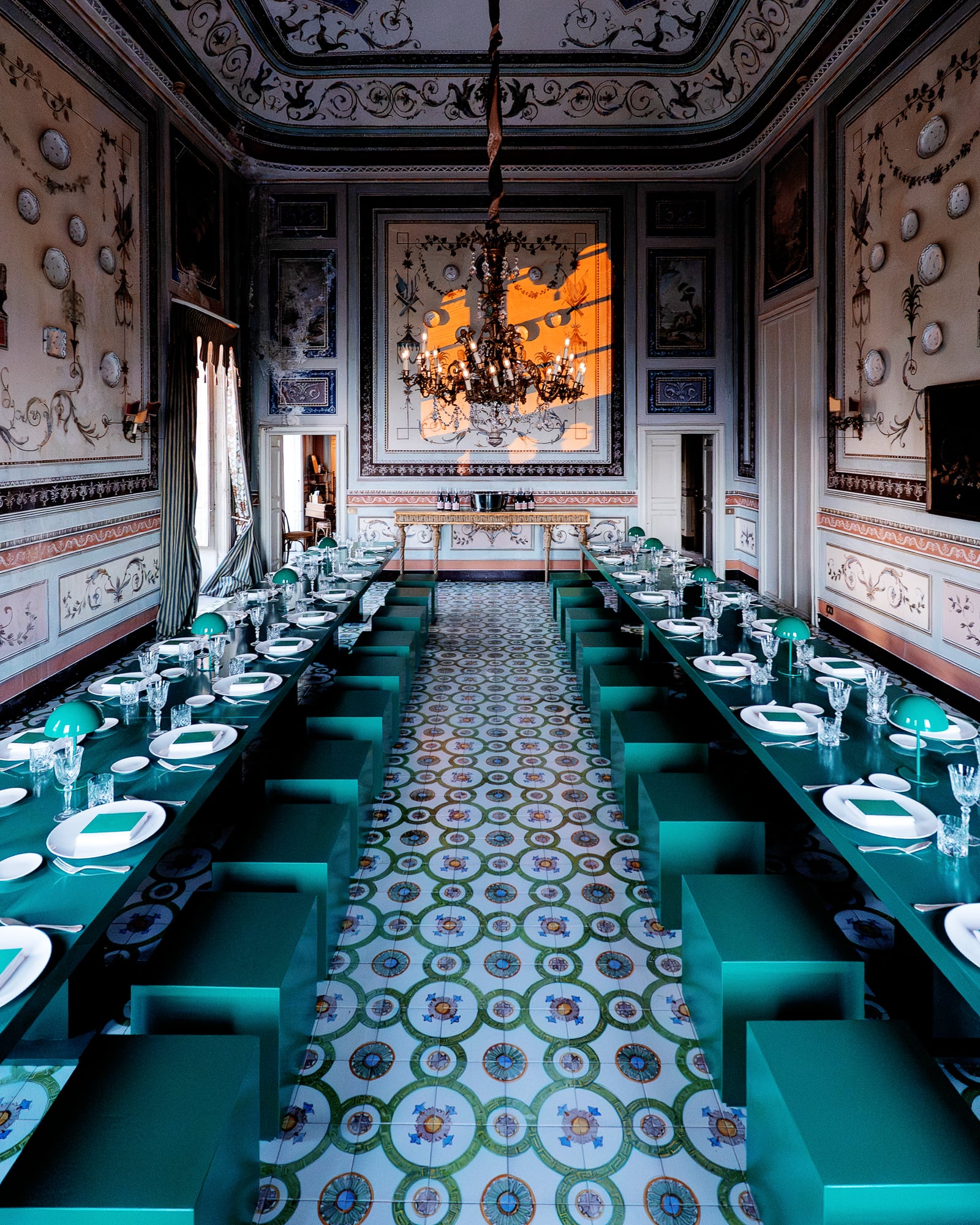 Longue galerie au sol en carreaux de céramique, tables vertes et lustre, dîner de gala à Palerme
